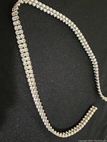 Full view of the necklace displaying the silver-tone metal chain with double rows of clear rhinestones against a black background.