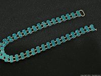 Full view of blue rhinestone dress jewelry laid out flat, showing length and metal clasp.