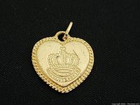 Front view of gold toned heart-shaped locket with crown design and LOVE engraving, showing textured border and bail for chain attachment.