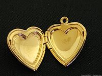 Opened view of gold tone puffy heart locket showing smooth interior surface.
