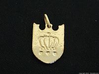 Photo of gold finished crown locket with three small hearts below the crown, set against black background showing texture and loop attachment.