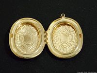Photo of the interior of the vintage oval locket showing symmetrical engraved patterns on both sides with two compartments for photos or keepsakes.