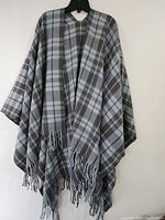 Two large gray and brown plaid shawls hanging on a black hanger showing full length and fringed edges.