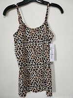 Front view of new women's leopard print top hung on a black hanger showing the full length and adjustable straps.