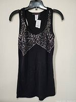 Full view of black sleeveless decorative women's top with sequin pattern on front.