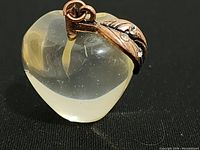 Close-up photo of clear heart-shaped pendant showing rose gold leaf detail with rhinestones.