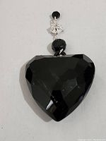 Front view of the black diamond-cut heart pendant showing faceted surface and attached beads.