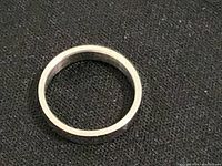 Image showing top-down view of a simple silver ring on a black background.