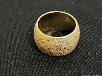 Top view of gold finish textured dome shaped ring showing detailed texture and width.