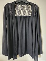 Full front view of black long sleeve women's top showing lace panel detail