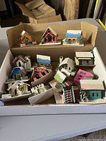 Box containing thirteen small vintage cardboard Christmas houses painted with snow and holiday colors
