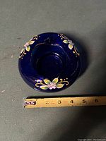 Top view of cobalt blue rose bowl with hand painted floral decoration and tape measure showing about 6-inch diameter.