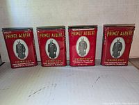 Front view of all four vintage Prince Albert tobacco tins showing red design and portrait.