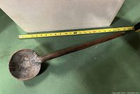 Photo of vintage wooden ladle with measuring tape showing approx 22 inches length