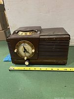 Front angle view showing full clock radio with measuring tape for size reference.