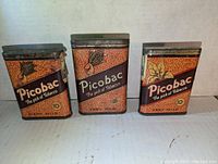 Front view of three vintage Picobac tobacco tins showing brand name, artwork, pricing, and vintage design details.