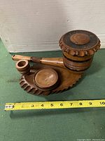 Front view of the wooden pipe ornament with tobacco holder, match holder, ashtray on carved wooden base, measuring approximately 10 inches long