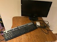 Acer monitor with keyboard and mouse on wooden surface, with cables visible