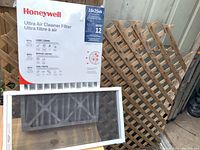 Photo of Honeywell Ultra Air Cleaner furnace filter and wooden lattice window screen leaning against a wall.