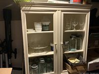 Image of painted china cabinet showing two upper doors with open shelves behind, missing glass, and lower storage area with drawers and cupboard door.