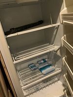 Interior view of Frigidaire freezer showing three wire shelves, one wire drawer, and door shelves.