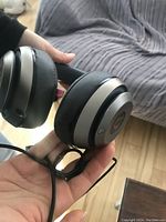 Close up of grey Beats wireless headphones showing cushioned ear pads, silver and black casing, and charging indicator lights.