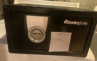 Closed front view of the black SentrySafe home safe showing the key lock and brand logo.
