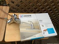 Brand new Moen Adler 87201 kitchen tap with box and installation instructions visible, tap chrome finished with single handle