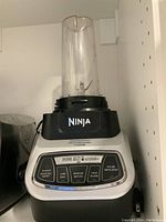 Ninja blender base with attached small blending container in place, showing control panel and branding.