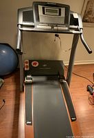 Front view of the NordicTrack treadmill showing the running deck and supporting frame in a home basement setting