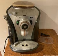 Front view of Saeco espresso machine showing control knob, drip tray, milk frother wand
