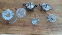 Overview photo of all six items on a wooden surface including silver plated sugar bowls, glass containers and accessories.