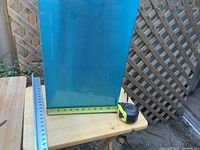 Stainless steel square tube standing vertically with a tape measure showing approximate height of about 22 inches.