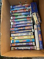 Top view of box showing stacked VHS tapes featuring Disney classics and other kids movies.