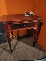 Full view of the sewing machine cabinet with foot pedal on top.