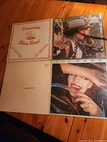 Four vinyl records on wooden surface: Downchild Blues Band - Live Deluxe, The Beatles, The Cars, and another album with a man in a hat on the cover.