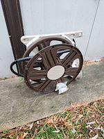 Wall-mounted garden hose reel with hose, showing side angle where hose is wrapped.