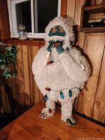 Full view of 32-inch tall outdoor abominable snowman figurine with white faux fur and blue face, wrapped in colored string lights needing replacement.