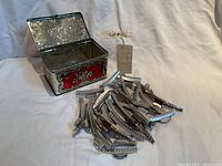 Open decorative metal tin with multiple vintage metal hair wave clips displayed next to it