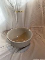 White ceramic baker's bowl shown with a white backdrop, displaying the bowl inside out with a smooth interior and fluted exterior.