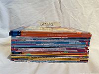 Side view of a stack of 26 children's books showing varying thickness and colorful spines with titles