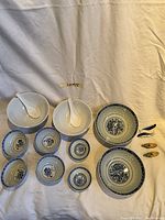 Top view of all bowls, spoons, sauce dishes, and fish-shaped cutlery holders arranged on cloth background.