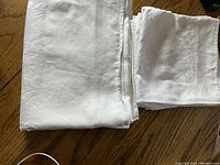 Folded white damask napkins and tablecloth showing material texture and fabric edges.