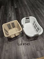 Photo of two laundry baskets on wood floor: one beige square basket and one white oval basket with gray handles.