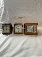 Three vintage nightstand clocks side-by-side showing clock faces and thermometer on one clock
