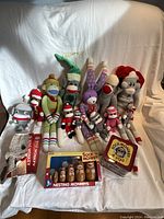 Full grouping of sock monkey teddy bears, pop up in box, nesting monkey set, and wine bottle covers displayed on white backdrop