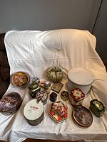 Full view of assorted vintage tins of different shapes and designs arranged on white fabric backdrop