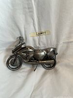 Front angled view of the metal motorcycle sculpture highlighting the detailed front and body including handlebars and exhaust pipe.