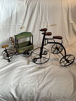 Photo showing two vintage children's decor items, a flower stand and an old fashioned tricycle, with their respective measurements 12x14 and 17x14 inches, against a white background.