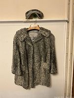 Full front view of vintage grey lambs wool textured ladies coat hanging on wooden hanger